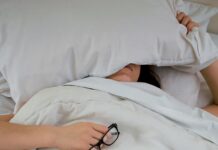 뱃살 타파의 신비, 수면의 역할은 무엇일까? 전문가들의 설명 person lying on bed while covering face with pillow and holding eyeglasses