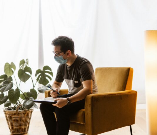 “에어컨 바람만 쐬면 머리가 띵해요”… 초여름 두통, 냉방병일 수 있습니다 a man sitting in a chair wearing a face mask
