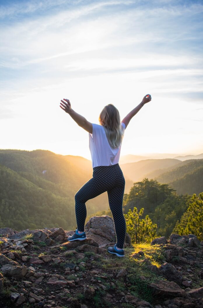 Photo by Danilo Ćalić woman in white shirt and black pants standing on rocky mountain during daytime