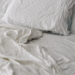 수면의 질을 높이는 생활 습관, 실천 가능한 작은 변화에서 시작 A rumpled white duvet and pillows on a bed.