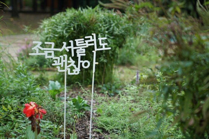 a sign that is in the grass near a flower