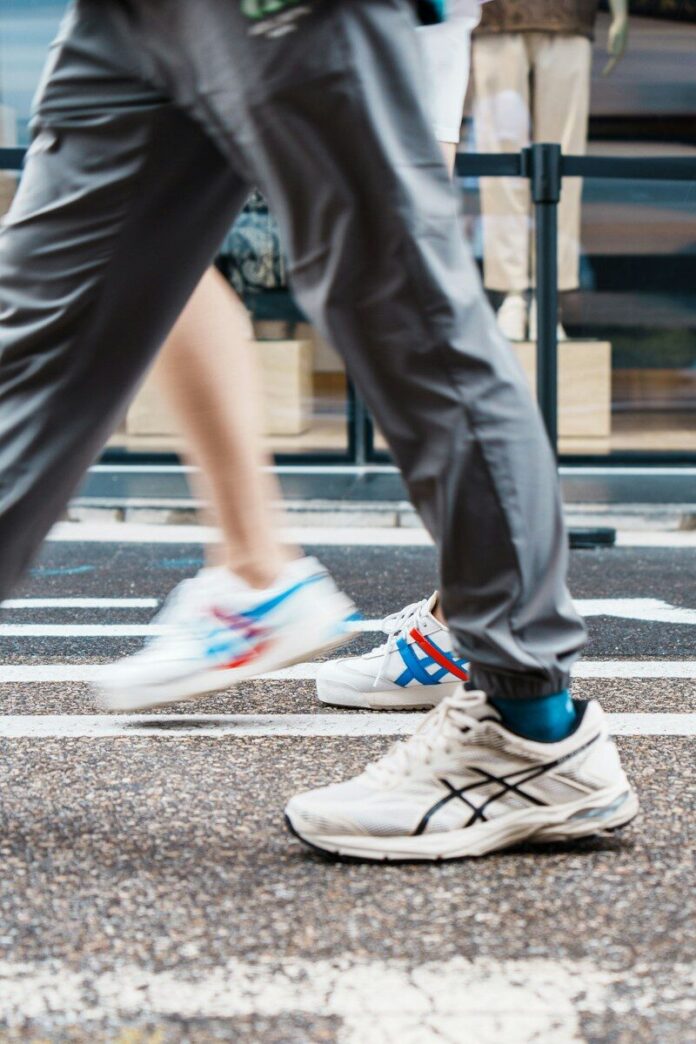 People walk on a crosswalk, showing only their legs